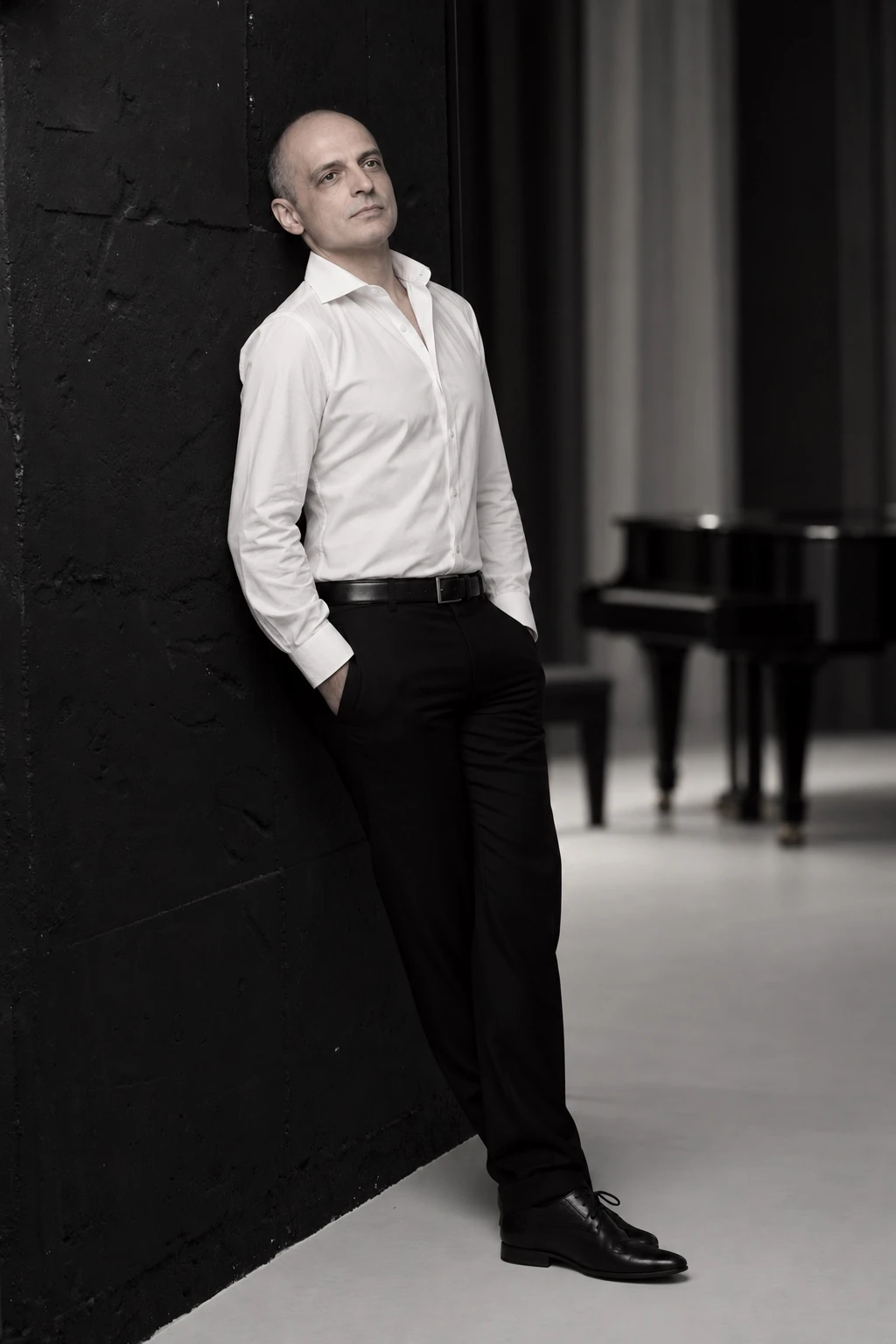 Ivan Yanakov in a white shirt beside a grand piano