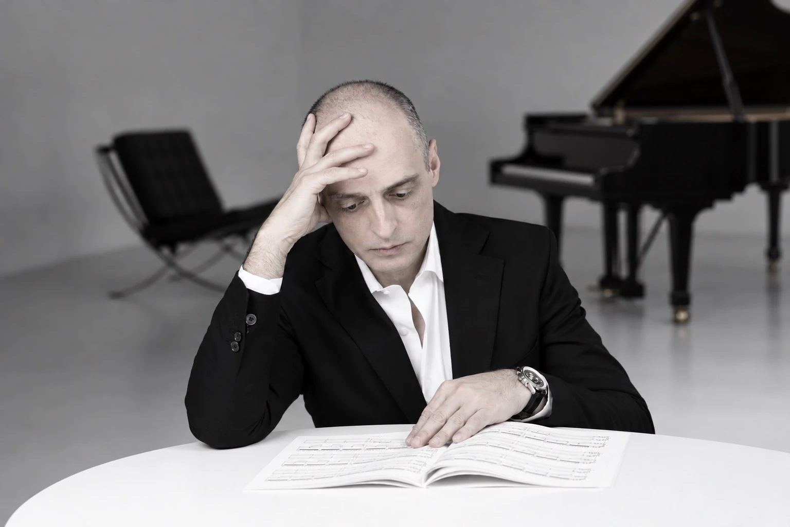 Ivan Yanakov studying an open music score with a grand piano behind him